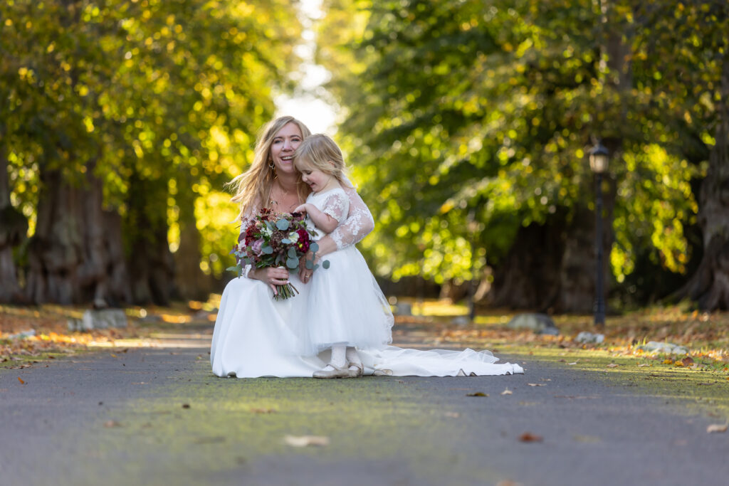 bride with flower girl, outside during autumn wedding